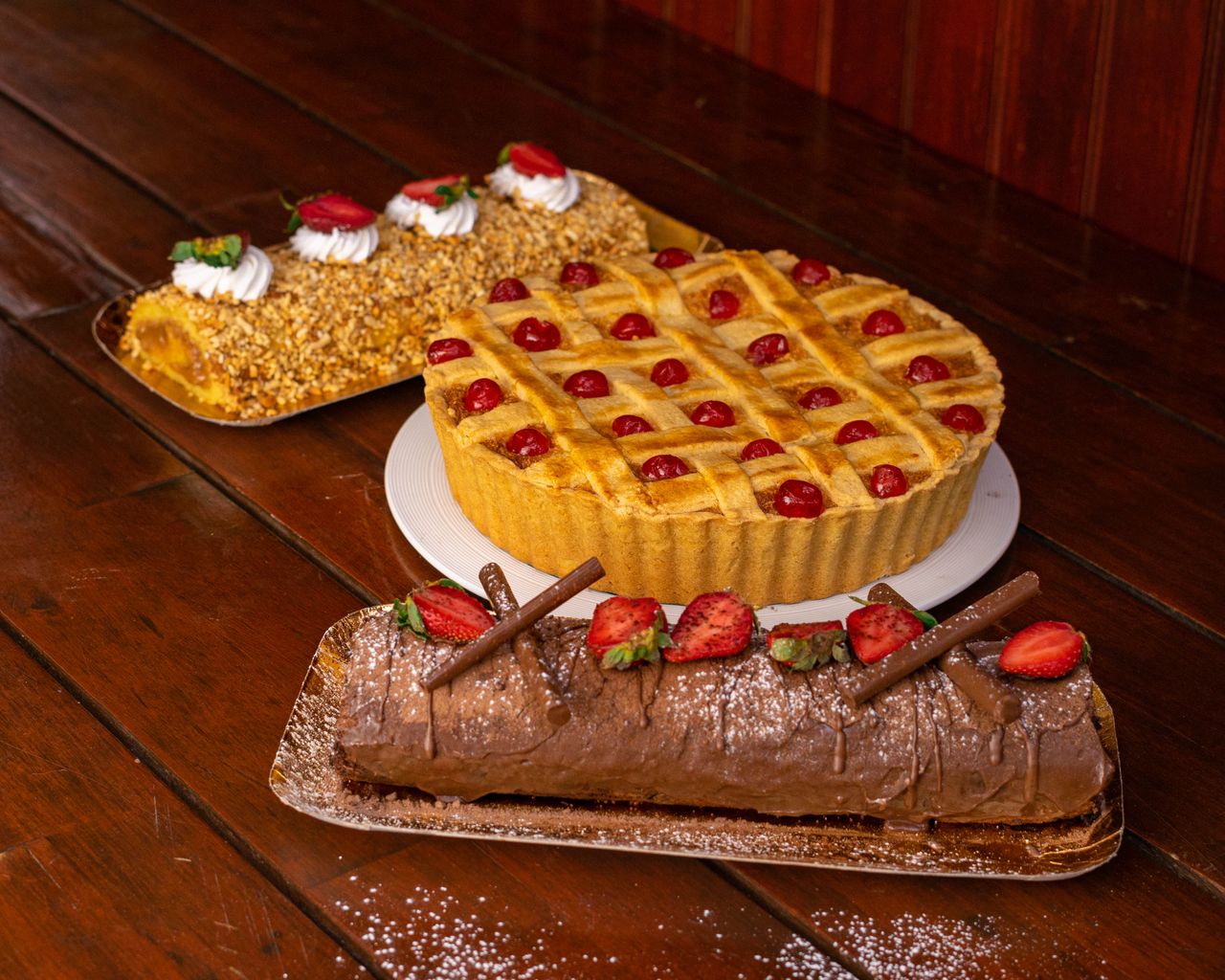 A variety of delectable homemade cakes and tarts displayed on a rustic wooden table, perfect for dessert lovers.